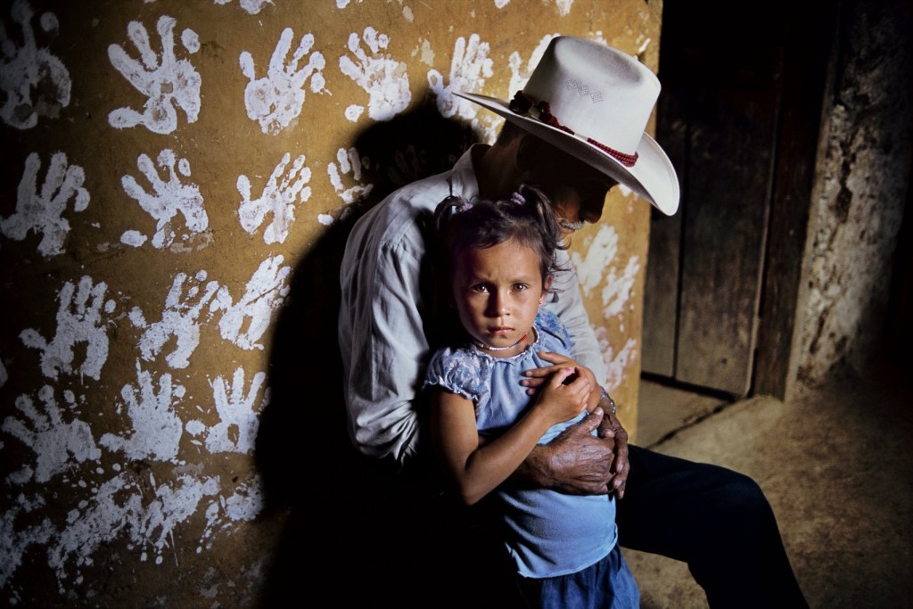 Steve McCurry, a man and his granddoughter in front of a wall decorated with hand prints, La Fortuna, Honduras, 2004