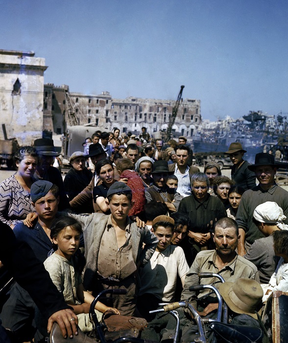 Sfollati italiani attendono in un punto di raccolta ad Anzio l’imbarco sulle navi che li porteranno a Napoli, giugno 1944. © National Archives And Records Administration